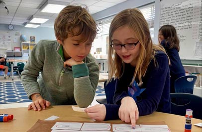 Boy and girl student pointing at math problem on a sheet together