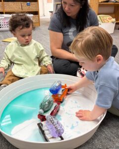 Teacher helping kids make a plastic bottle train in a tub
