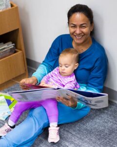 Teacher reading a book to a child at Concord Cubs